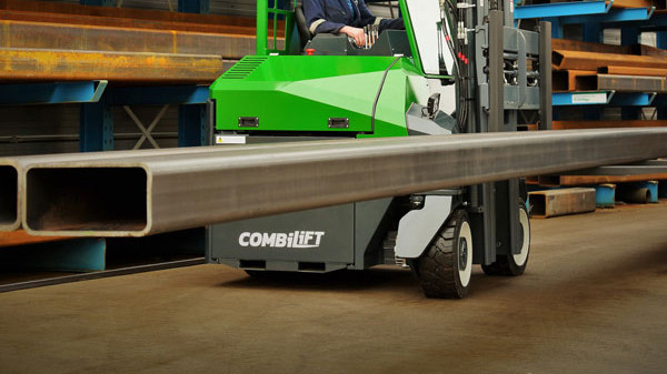 Operator driving a green Combilift forklift in a warehouse.
