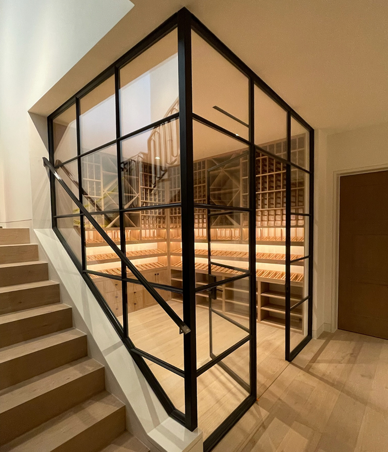 Modern glass-enclosed wine cellar under a staircase