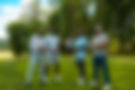 Four men posing with golf clubs on a green sunny course