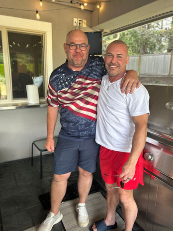 Two men smiling, one in a patriotic shirt