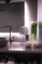 Modern bathroom sink with mirror, flowers and accessories, close-up shot.