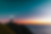 Lighthouse standing tall on a cliff during a vibrant sunset