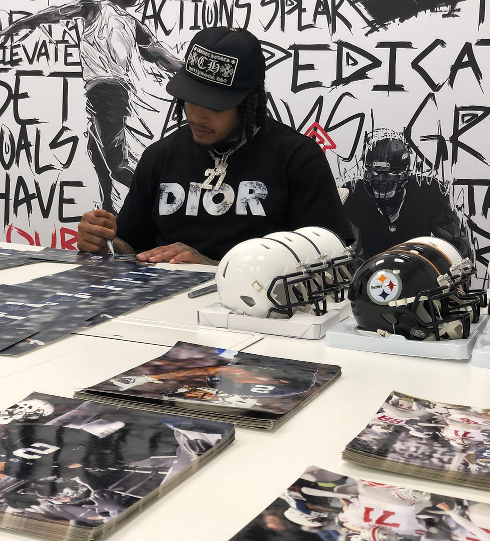 Man in a Dior shirt signing football memorabilia.