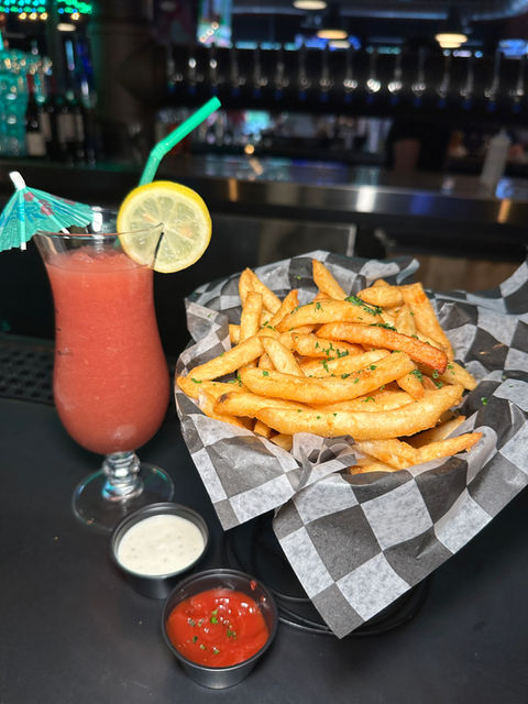 Fries and a pink cocktail with lemon and umbrella