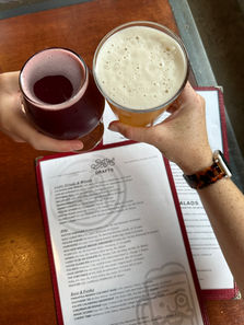 Hands holding a beer and a dark drink over a menu