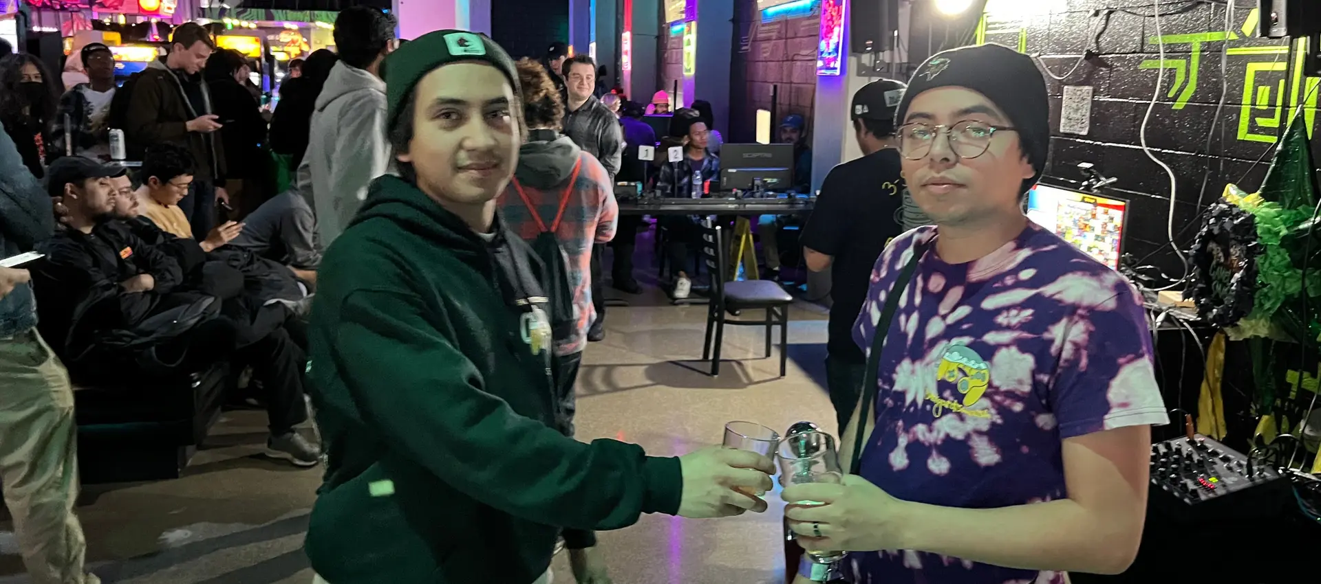 two people toasting their beers a an arcade