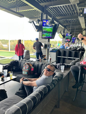 Man relaxing at Topgolf, watching sports on TV