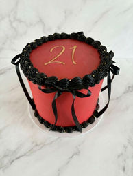 red and black buttercream cake, black buttercream borders with black ribbons, edible gold pearls