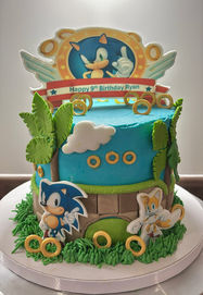 Sonic Themed cake, buttercream sky with fondant details, classic sonic two toned pathway, gold fondant rings, fondant clouds and palm trees featuring Sonic the hedgehog and knuckles. Personalised sonic fondant topper