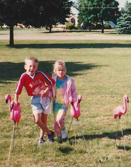 Young @mrcodywest and his sister standing with sass in childhood home front yard decorated with pink flamingo