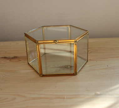 zu sehen ist ein Ringkästchen aus Glas mit goldenen Seiten.
