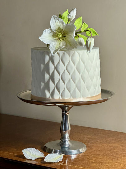 White Single Tier Cushion patterned Wedding cake, by chipping Campden Cakes by Rebecca. Topped with an Edible clematis spray.