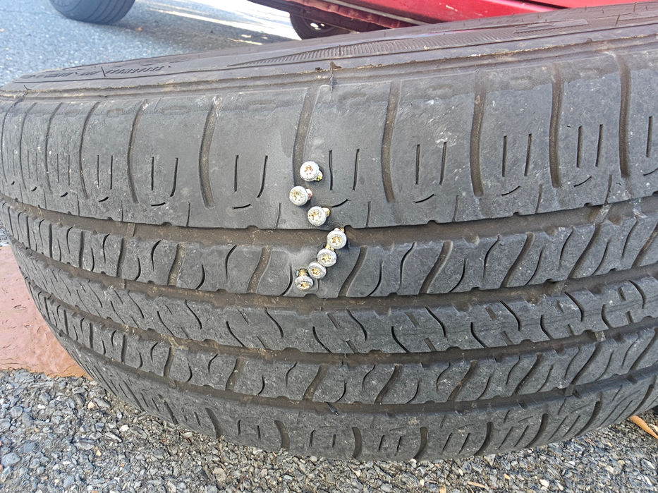 Technician completing a quick roadside tire change and spare tire installation on a flat wheel