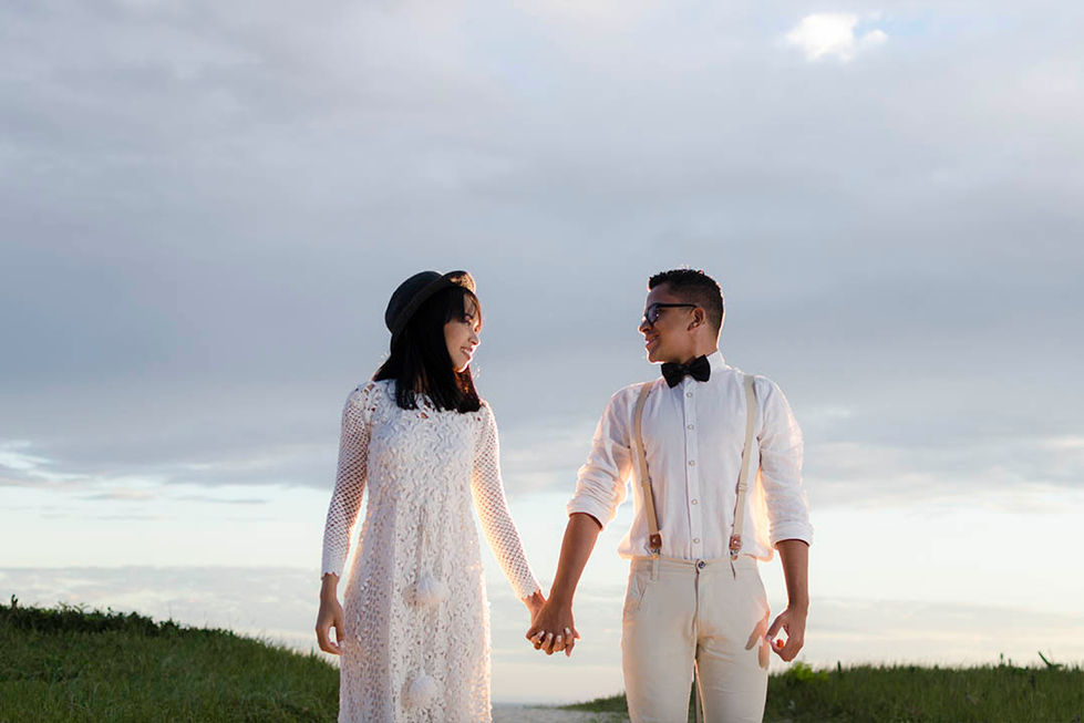 casal se olhando na praia, com roupa retrô e o monte ao fundo