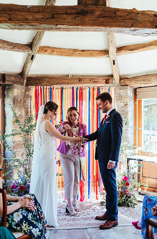 wedding celebrant, Rachael Meyer ties hand fasting ribbons at colourful wedding
