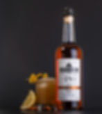 Low sugar Amaretto Sour cocktail made with Dapper Barons Amaretto next to the bottle