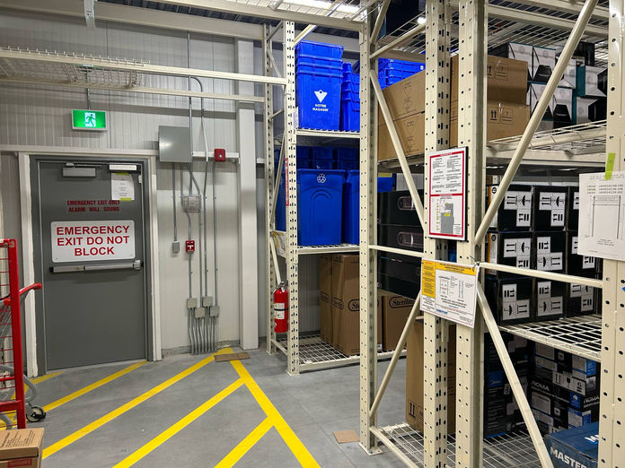 Example of evac signs being installed in critical locations within a warehouse space.