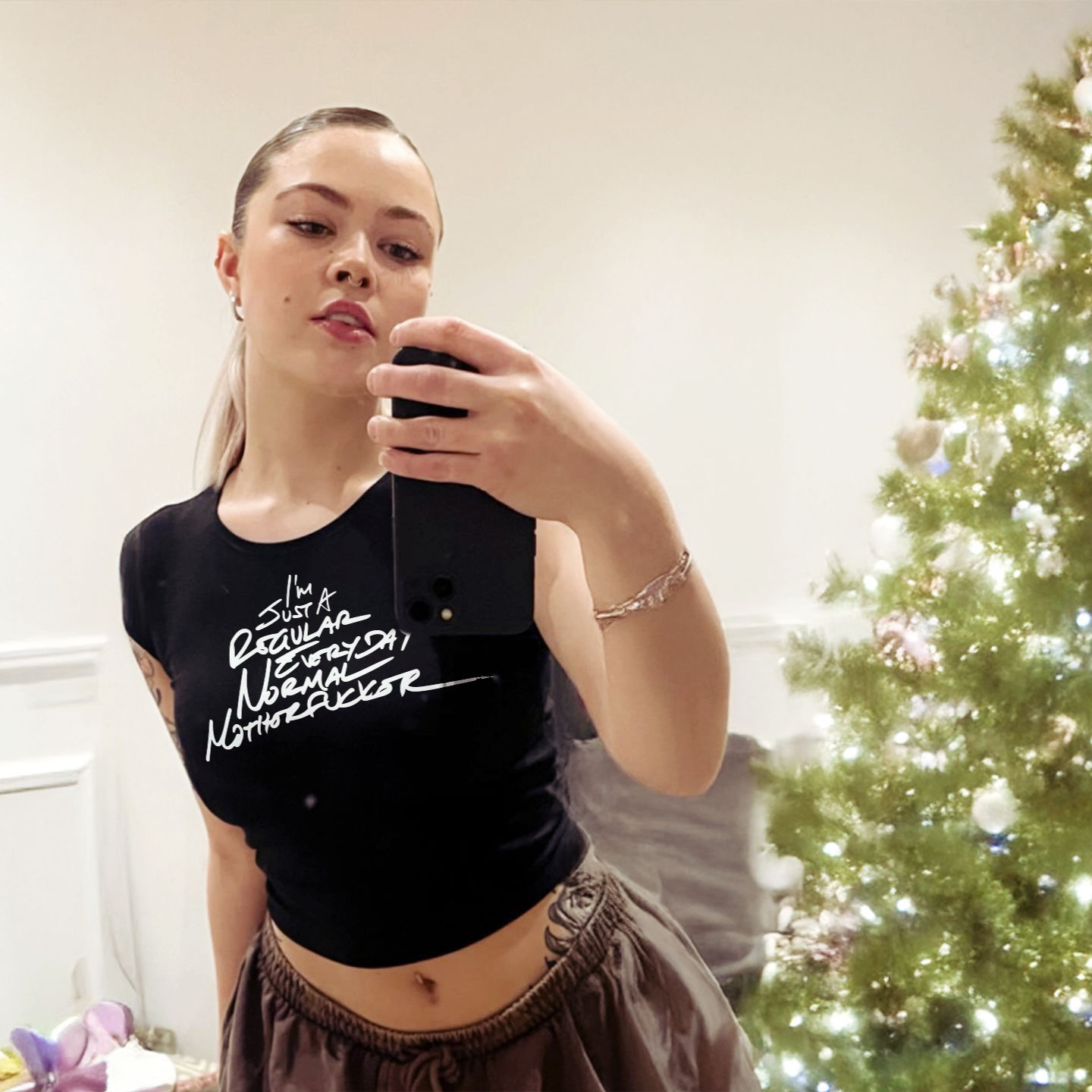 Model taking a mirror selfie wearing the tee with sweatpants, exuding casual confidence.