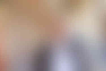 a woman wearing a necklace and a white shirt smiles