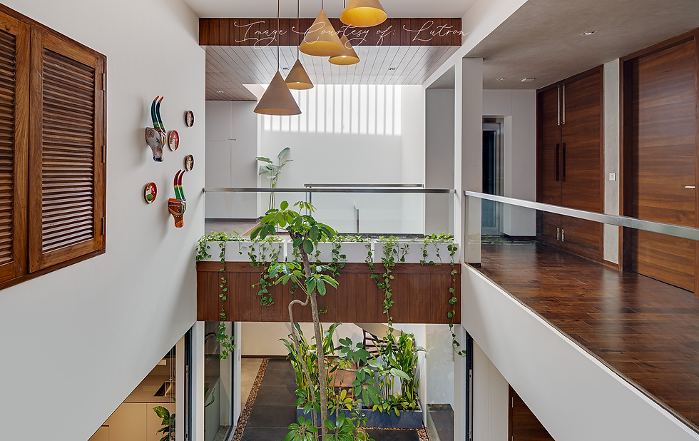 Modern interior with wooden accents, green plants, wall decor, and cone-shaped lights. Indoor garden visible below glass railing.