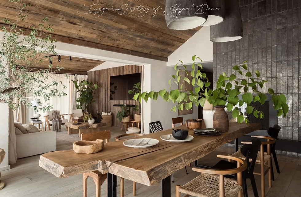 Rustic dining room with a wooden table, plants, woven chairs, and ceramics. Natural wood tones and soft lighting create a cozy atmosphere.
