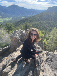 A woman is posing for a picture at the top of a mountain.