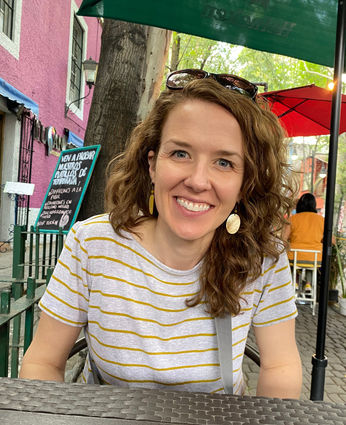 Woman sitting at a table looking into the camera and smiling.