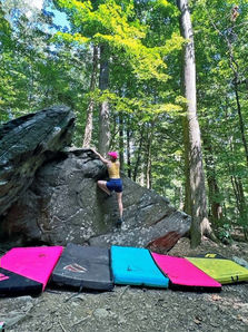A woman is bouldering outdoors.