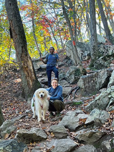 Woman, man, and dog posing for picture while hiking.