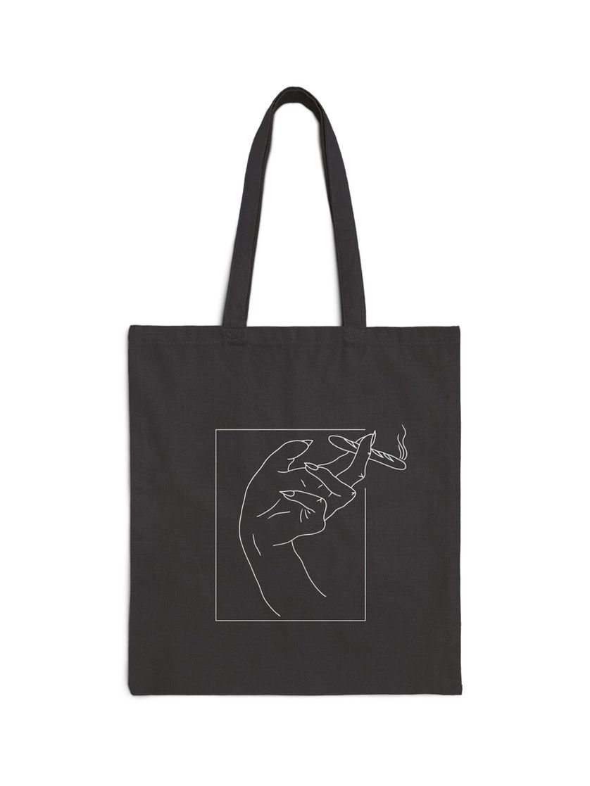 Black canvas tote bag featuring white line art of a hand holding a steaming baguette like a joint.