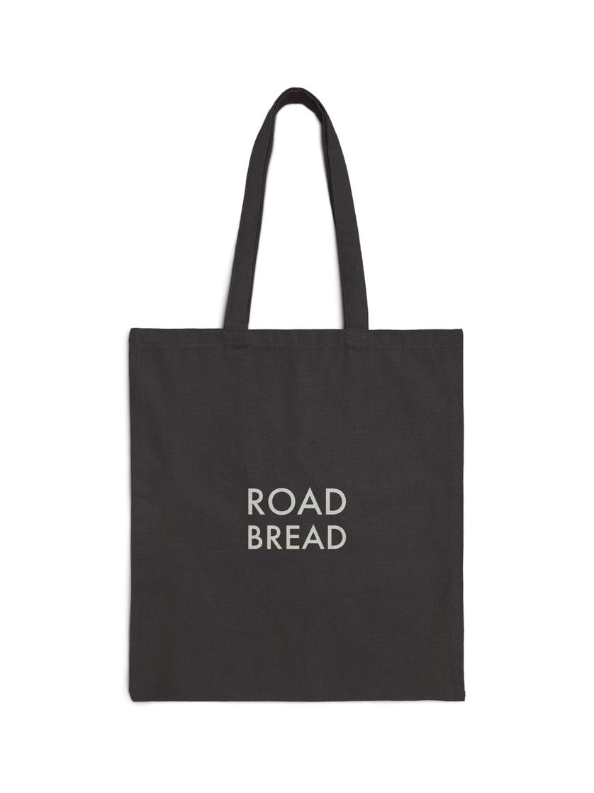 Back of black canvas tote bag with the Road Bread logo printed in white across the center.