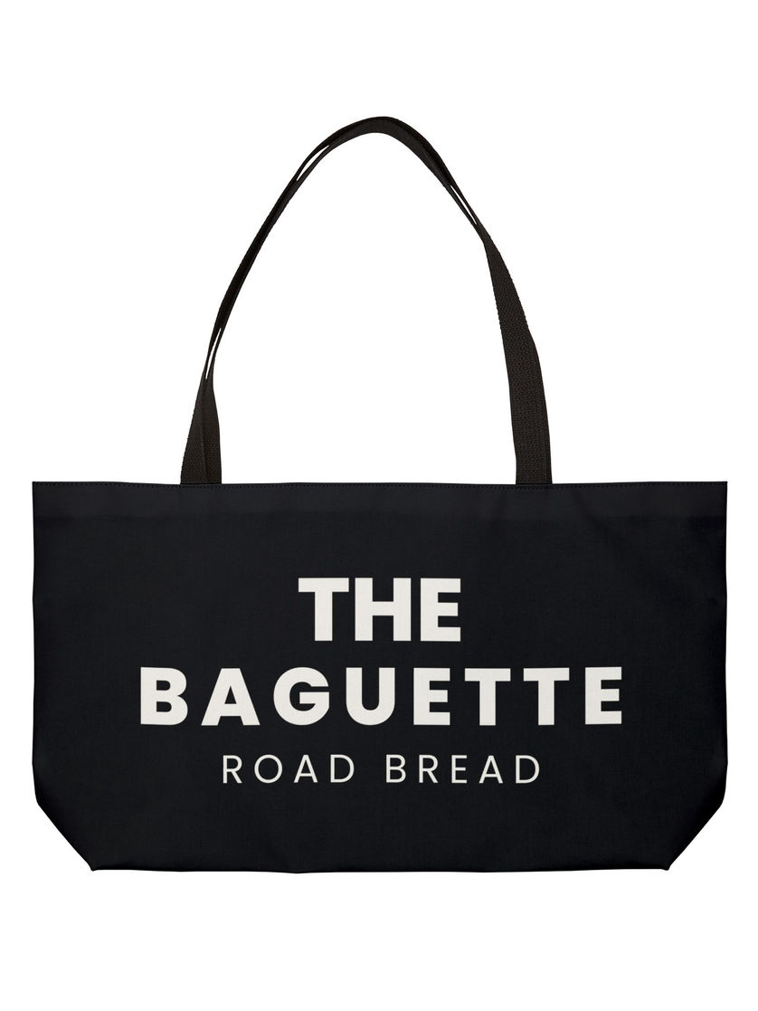 Front view of large black canvas tote bag with white block text reading “THE BAGUETTE ROAD BREAD”