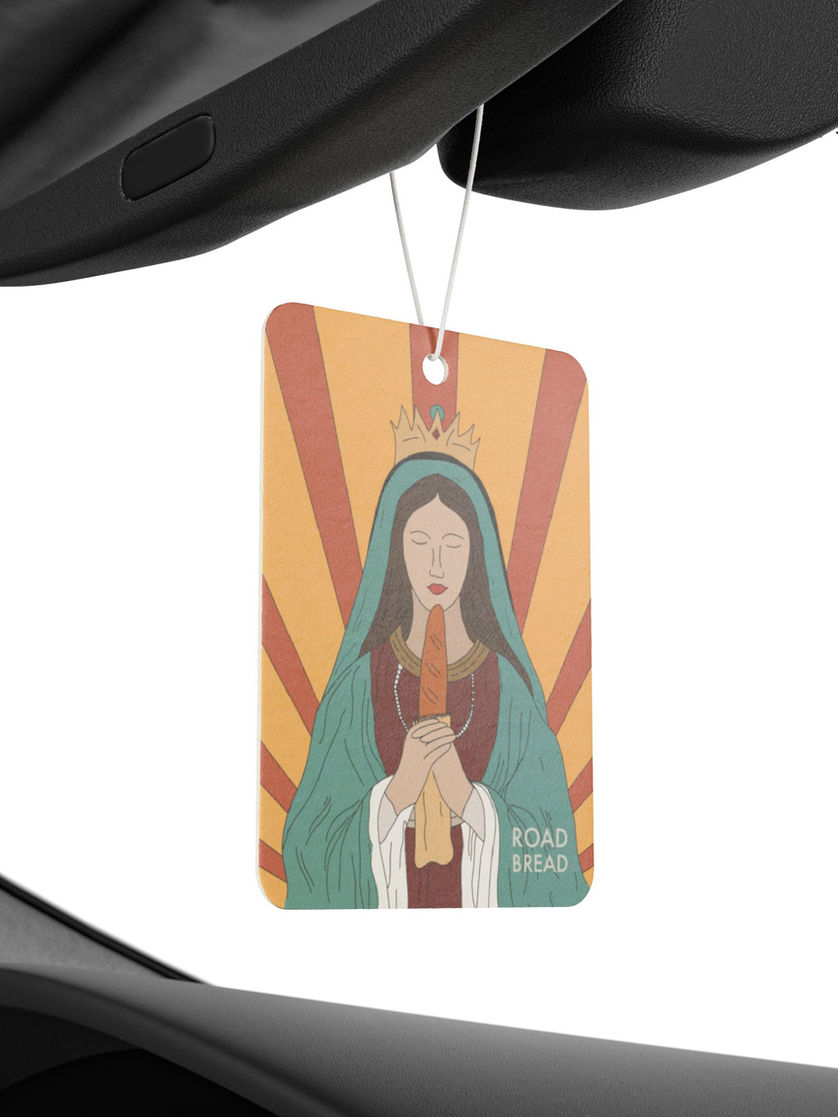 Air freshener hanging from a car mirror with playful religious design
