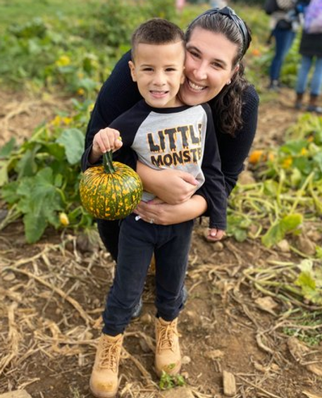 mom and son pose together with pumpkin