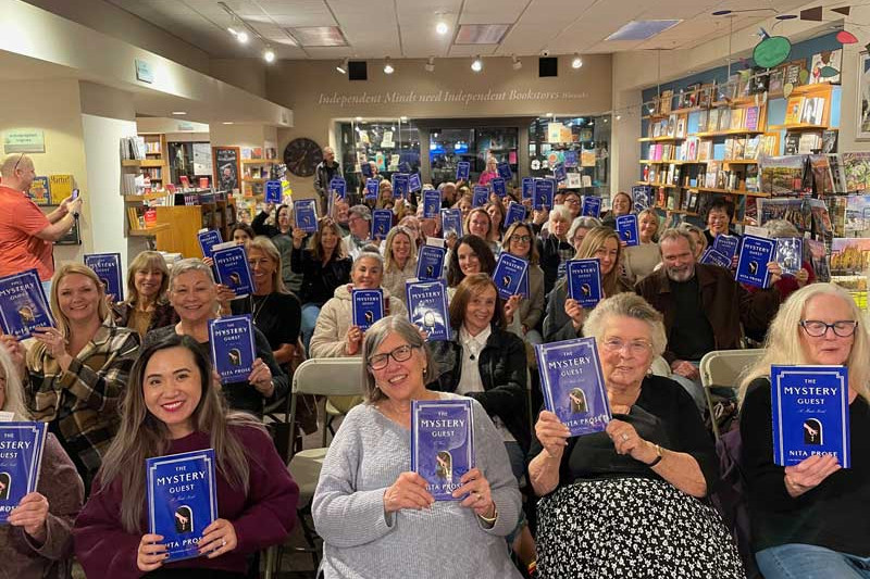 Crowd at a bookstore in La Jolla, California, holding up copies of The Mystery Guest.