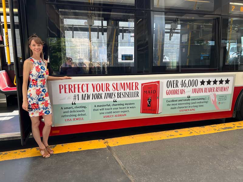 Nita poses in front of a bus ad for The Maid in Toronto, Canada