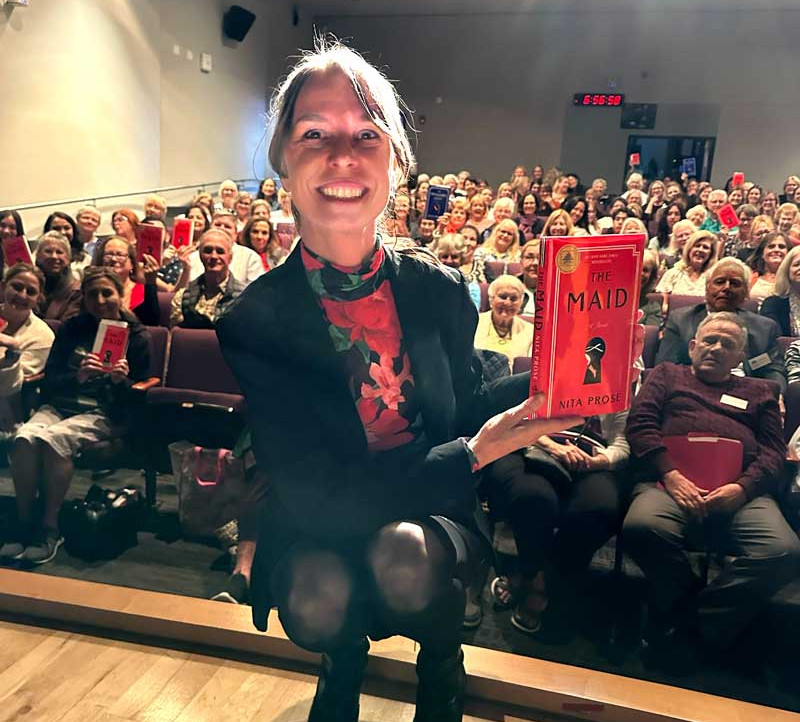 Nita poses in front of a large crowd with her copy of The Maid