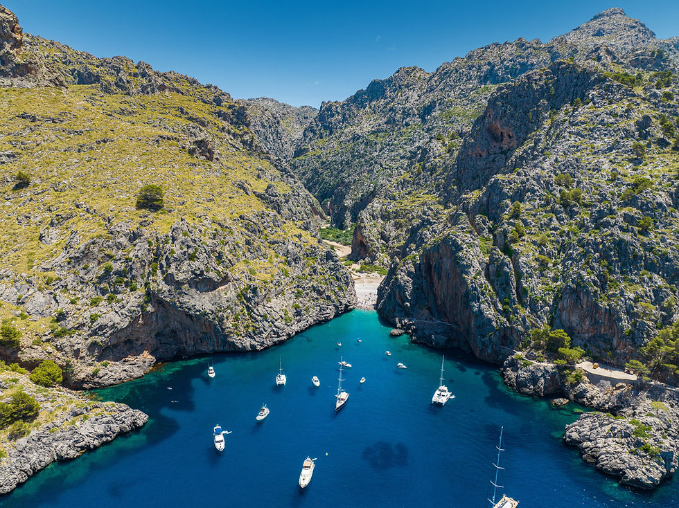 Aerial view of Sa Calobra and Torrent de Pareis in Mallorca, featuring turquoise waters, dramatic cliffs and boats anchored in one of the island's most iconic natural landmarks.