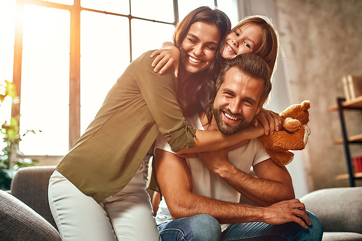 happy-dad-mom-with-their-cute-daughter-teddy-bear-hug-have-fun-sitting-sofa-living-room-ho