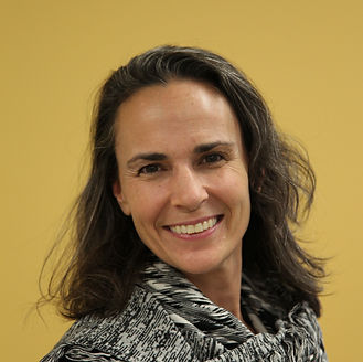 dawh thomas smiling at camera. Woman smiling wearing a scarf with yellow background