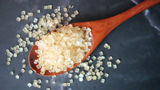 Un cuillère remplie de grains de sucres