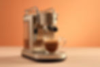 Máquina de espresso prateada servindo café em xícara de vidro, com fundo laranja suave.