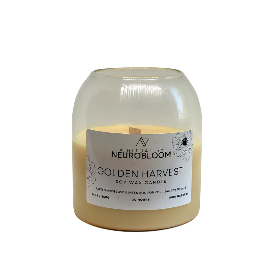 Hand-poured soy wax Golden Harvest Candle on a rustic wooden table with fall leaves.