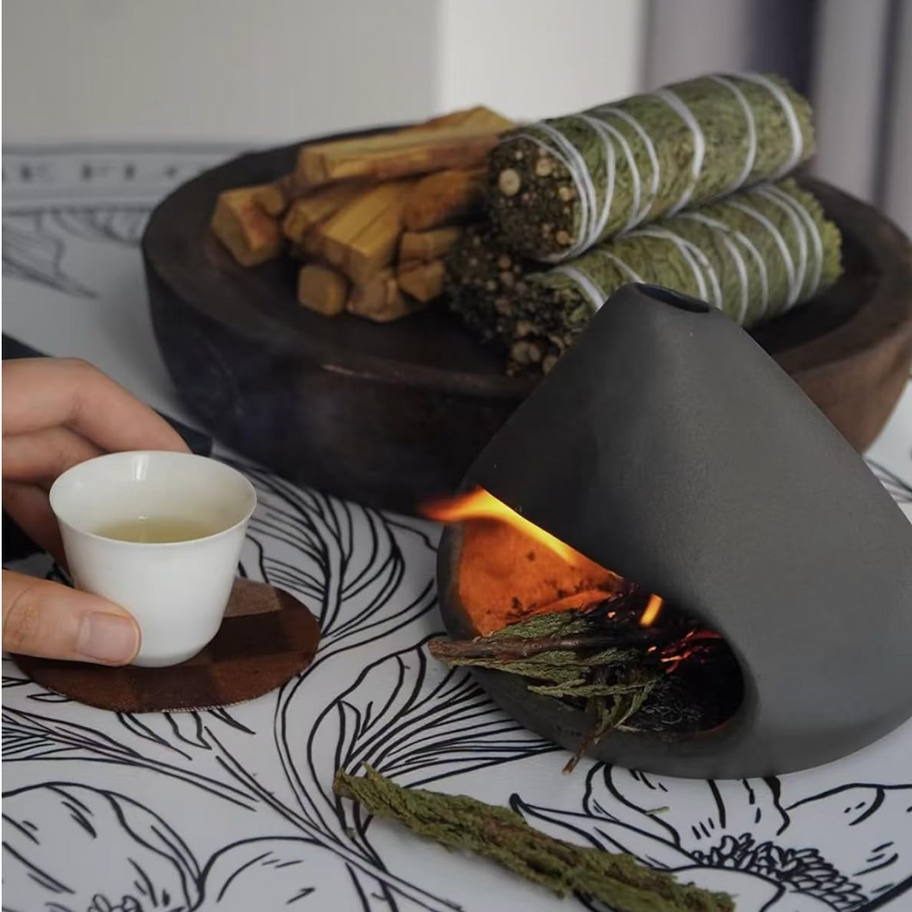 Close-up of palo santo stick burning in a ceramic holder with smoke rising in a calming atmosphere.