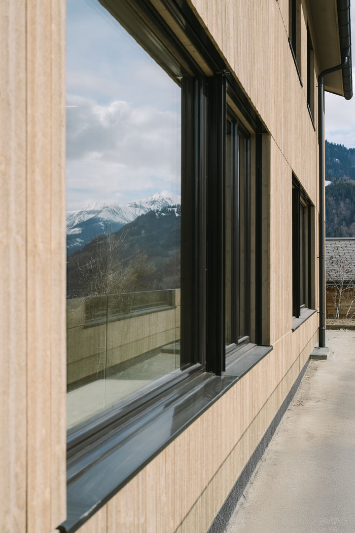 Detailansicht eines massiven Holzfensterrahmens mit Blick auf das Bergpanorama.