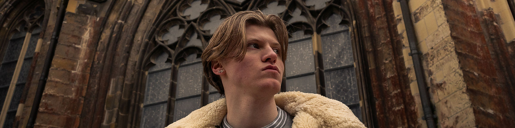 Stoer portret van een jongeman met een kerk als achtergrond