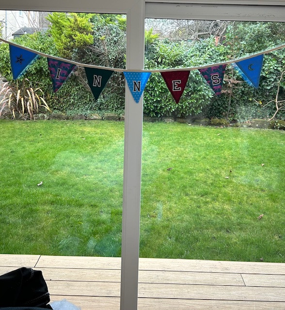 Handmade bunting made by child with his name on hanging in window.