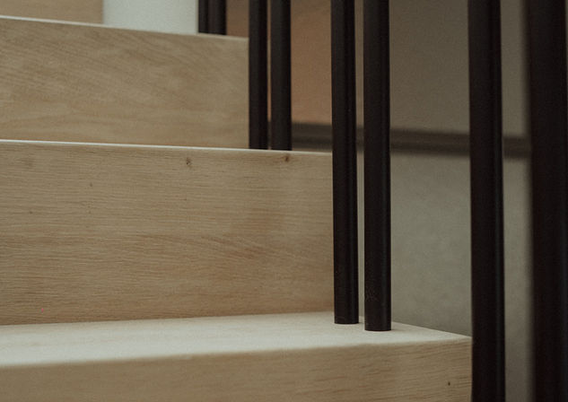 Detail van trap, houten wand en donker metalen binnenschrijnwerk.