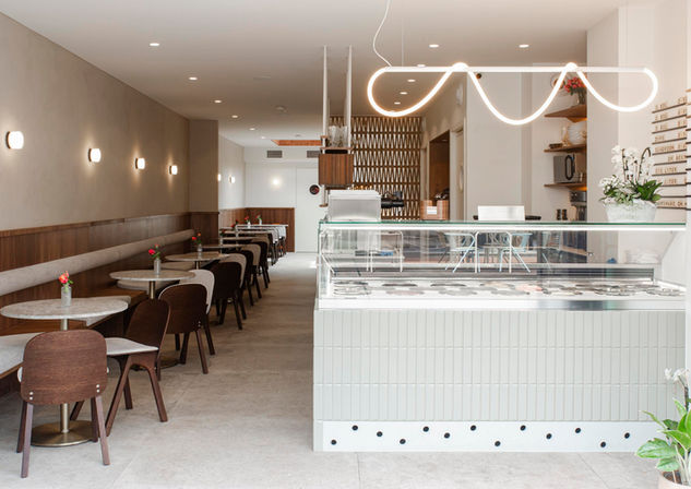 Overzicht van het interieur van een ijssalon met zitplaatsen, maatwerk en warme natuurlijke tinten.