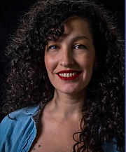 Headshot Melanie Silva. Brazilian woman with long curly brown hair.
